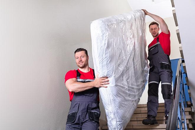 workers transporting a box spring out of a building in Chester Heights